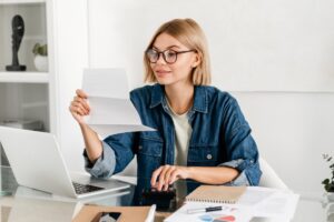 Young caucasian woman paying domestic bills, making calculations at home desk.